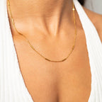 Woman wearing a bar chain necklace and white top