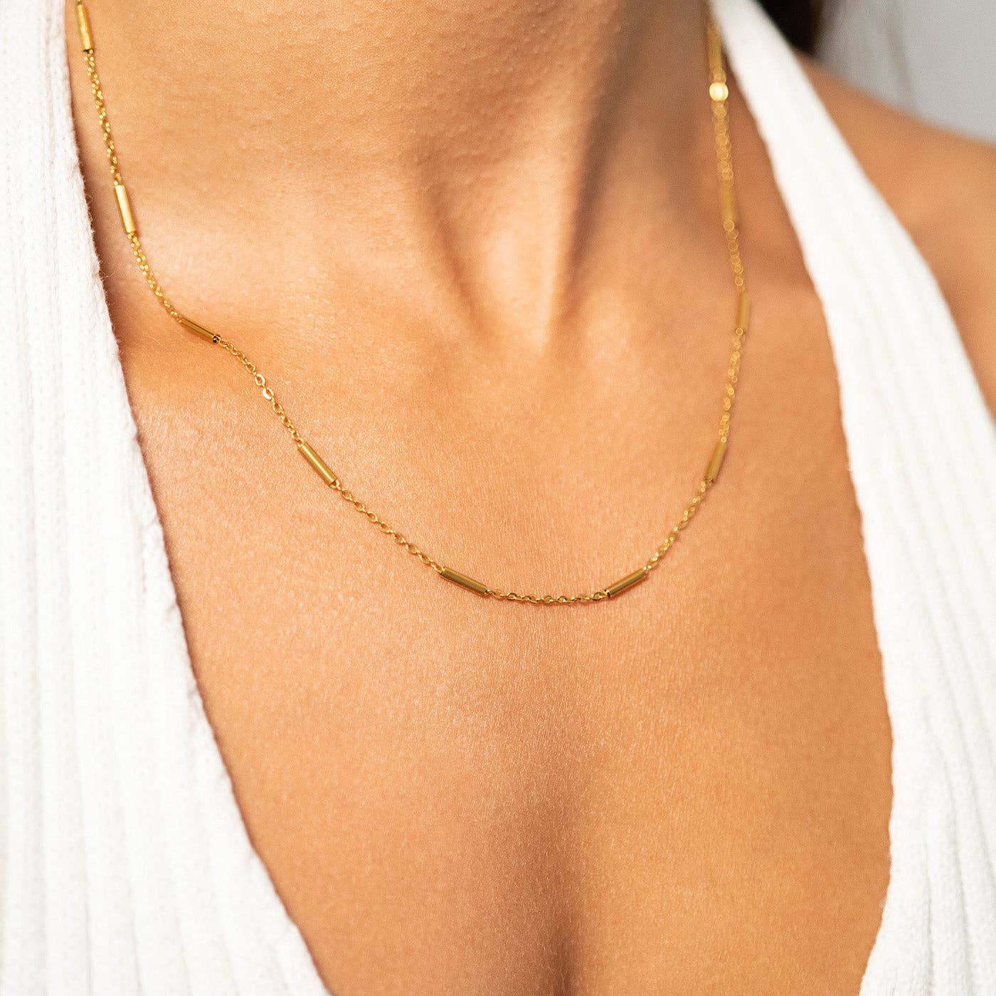 Woman wearing a bar chain necklace and white top