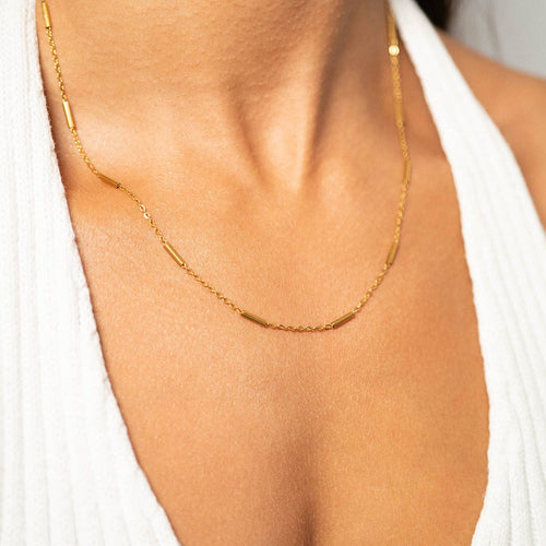 Woman wearing a bar chain necklace and white top
