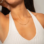 Woman wearing a bar chain necklace and white top