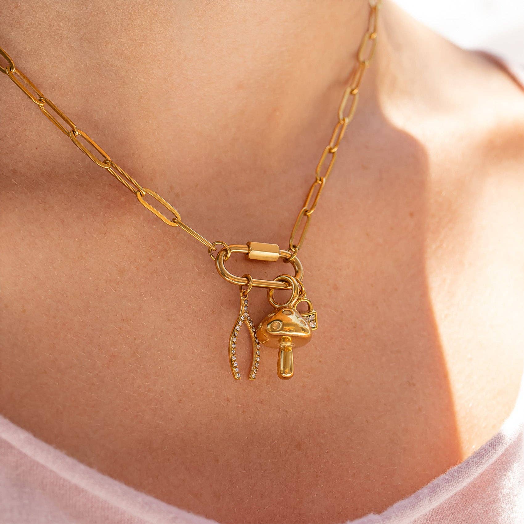 Woman wearing a paperclip carabiner gold necklace with charms