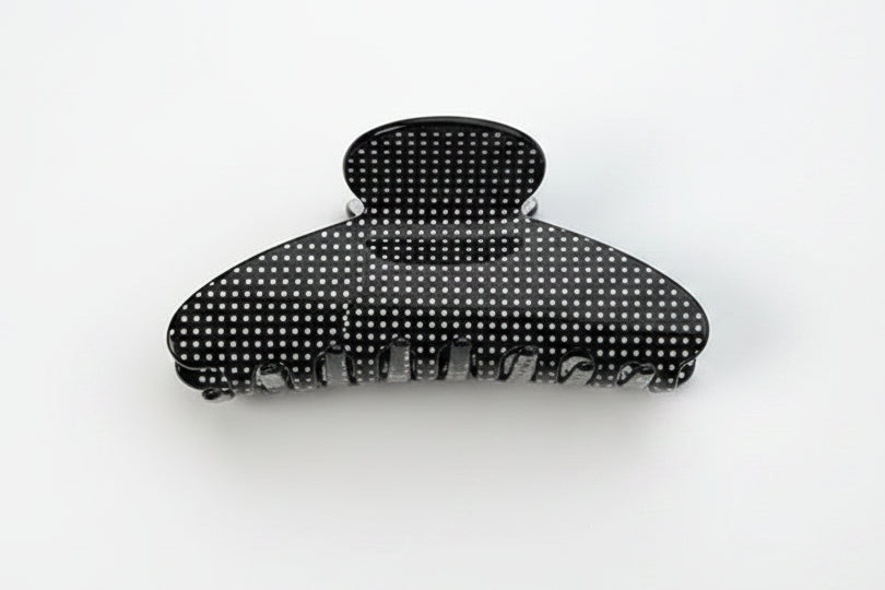 A black claw hair clip with white polka dots on a white background