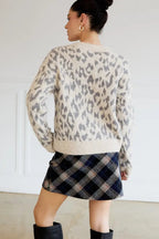 Woman wearing a leopard print sweater indoors.