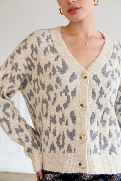 Woman wearing a leopard print cardigan with a plain background