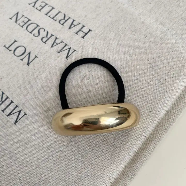 Gold metal hair tie on a white background