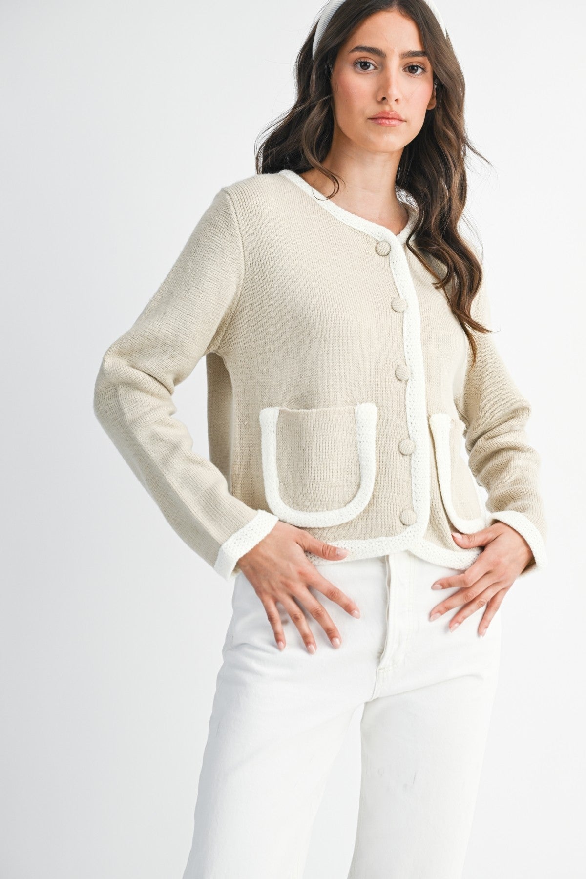 Woman wearing a lt. taupe and ivory cardigan  and white pants on a plain background