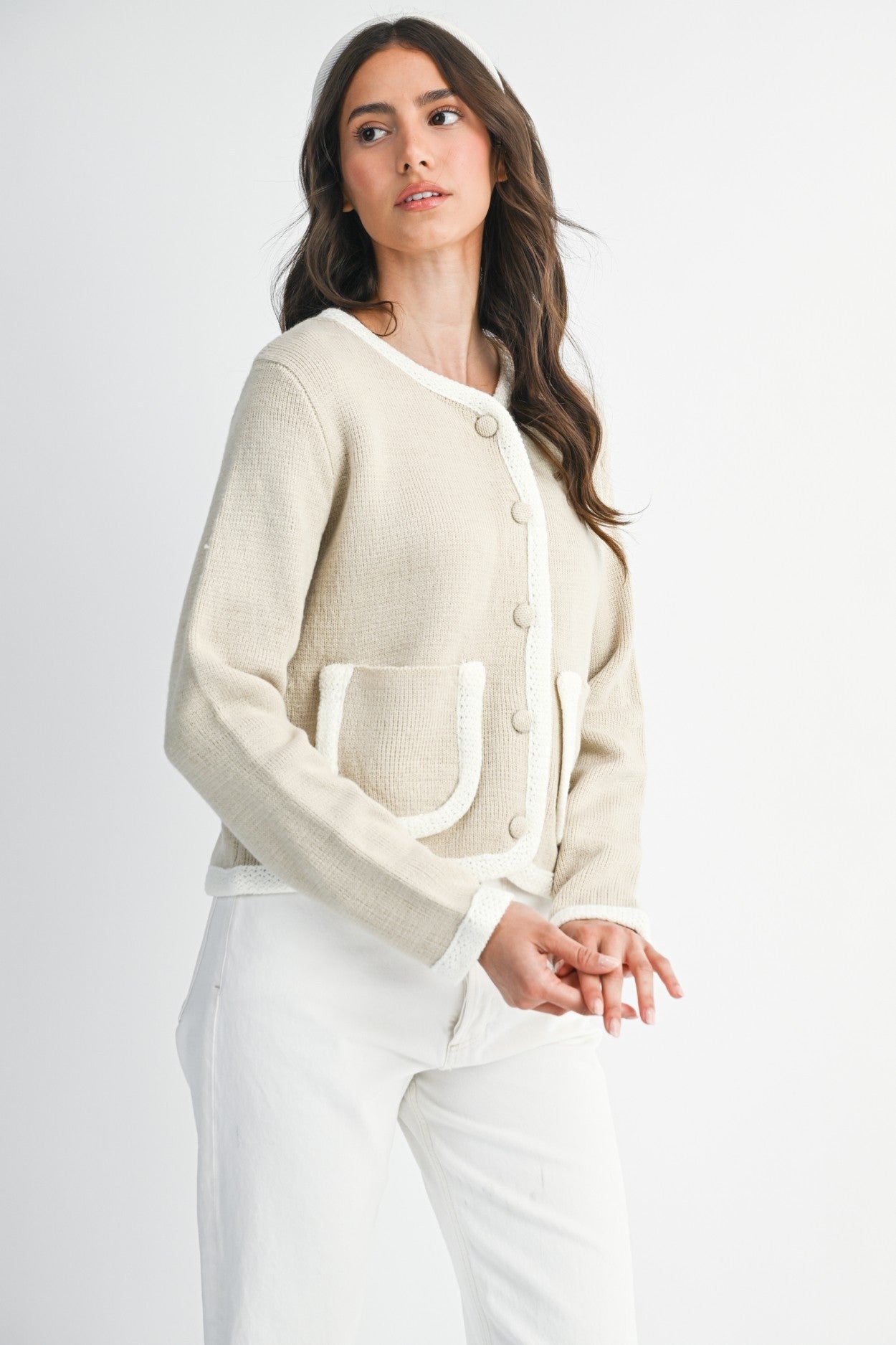Woman wearing a lt. taupe and ivory cardigan and white pants on a plain background