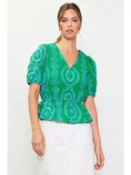 Woman wearing a green with blue embroidery top on a white background