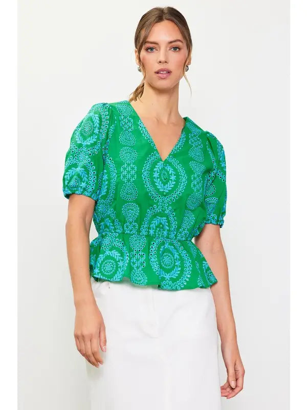 Woman wearing a green with blue embroidery top on a white background