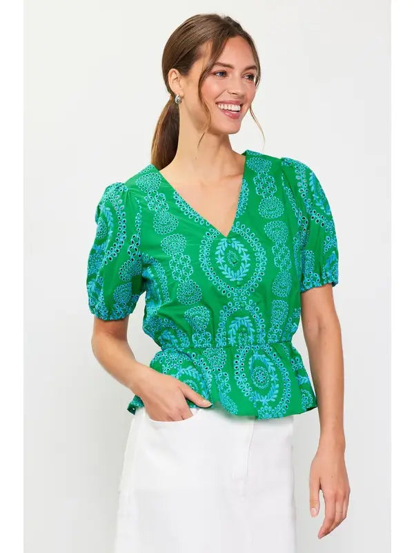 Woman wearing a green with blue embroidery top on a white background