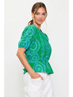 Woman wearing a green with blue embroidery top on a white background