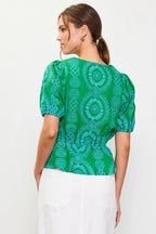 Woman wearing a green with blue embroidery top on a white background