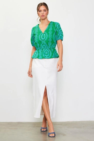 Woman wearing a green with blue embroidery top on a white background