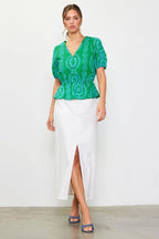 Woman wearing a green with blue embroidery top on a white background