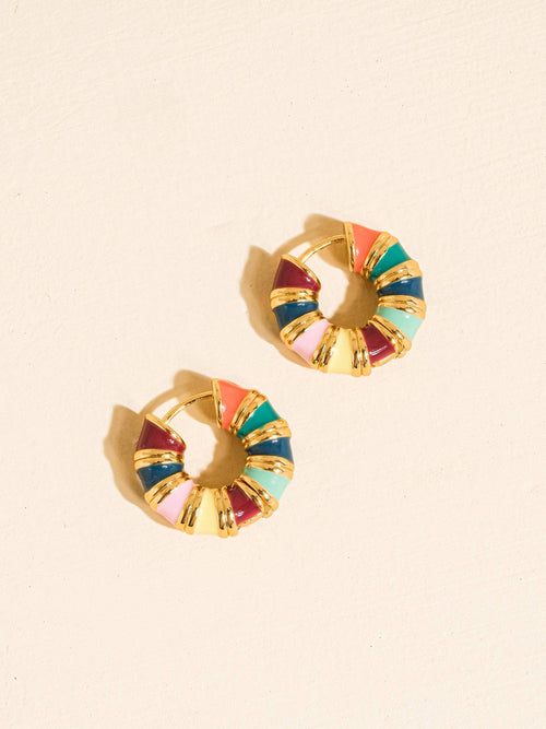 A pair of gold hoop earrings with colorful segmented enamel details in pink, orange, teal, blue, and burgundy, displayed on a light beige textured background.