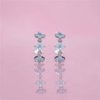 Pair of floral earrings with blue and silver details on a pink background