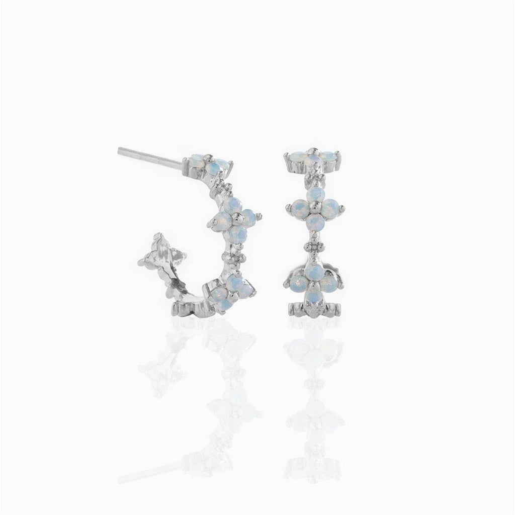 Silver plated hoop earrings with blue stones in a flower design on a white background