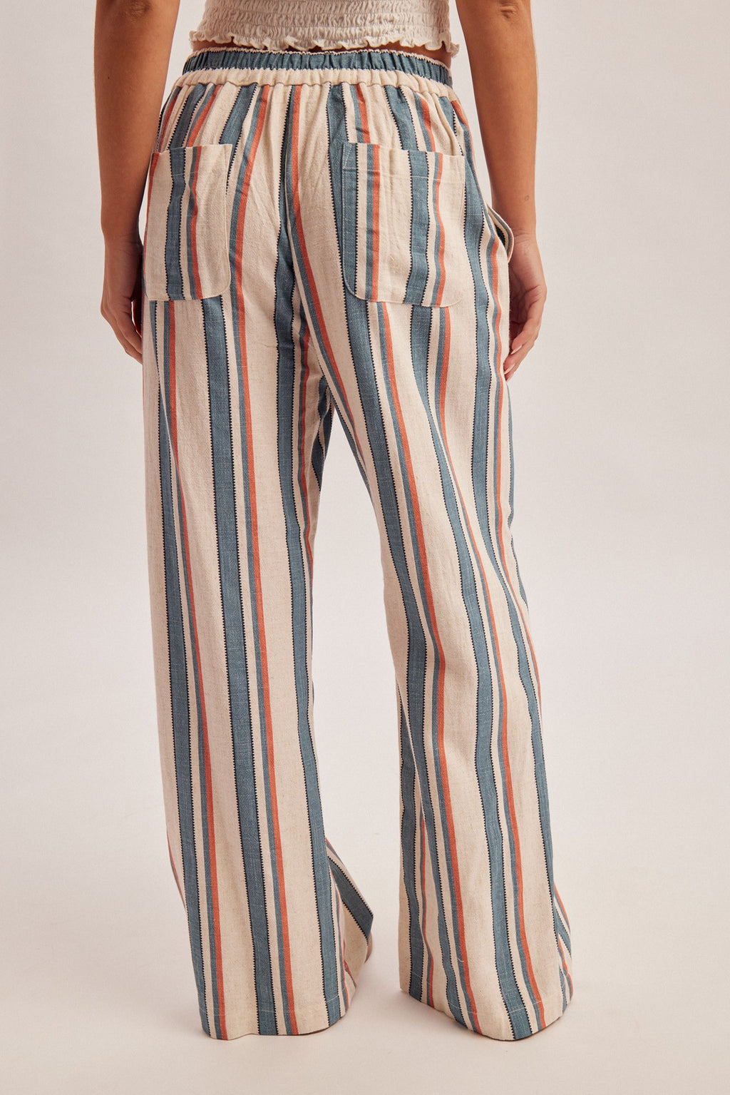 Woman wearing denim blue and red stripe linen feel pants on a gray background