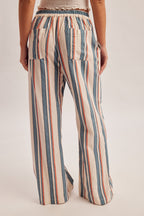 Woman wearing denim blue and red stripe linen feel pants on a gray background