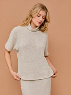 Woman wearing natural textured knit turtle neck short sleeve top on a beige background