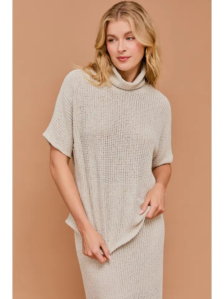 Woman wearing natural textured knit turtle neck short sleeve top on a beige background