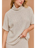 Woman wearing natural textured knit turtle neck short sleeve top on a beige background