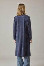 Back view of a woman wearing a navy faux suede duster coat with jeans against a grey background