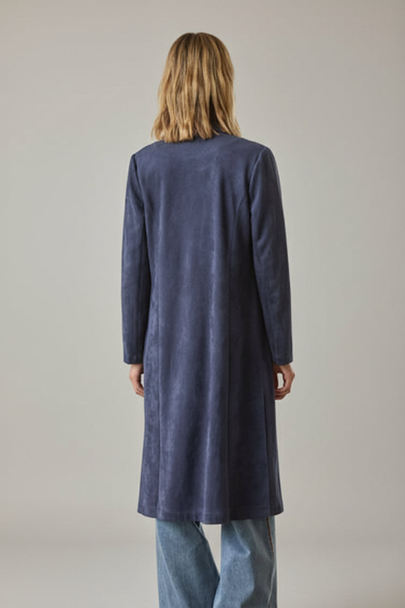 Back view of a woman wearing a navy faux suede duster coat with jeans against a grey background