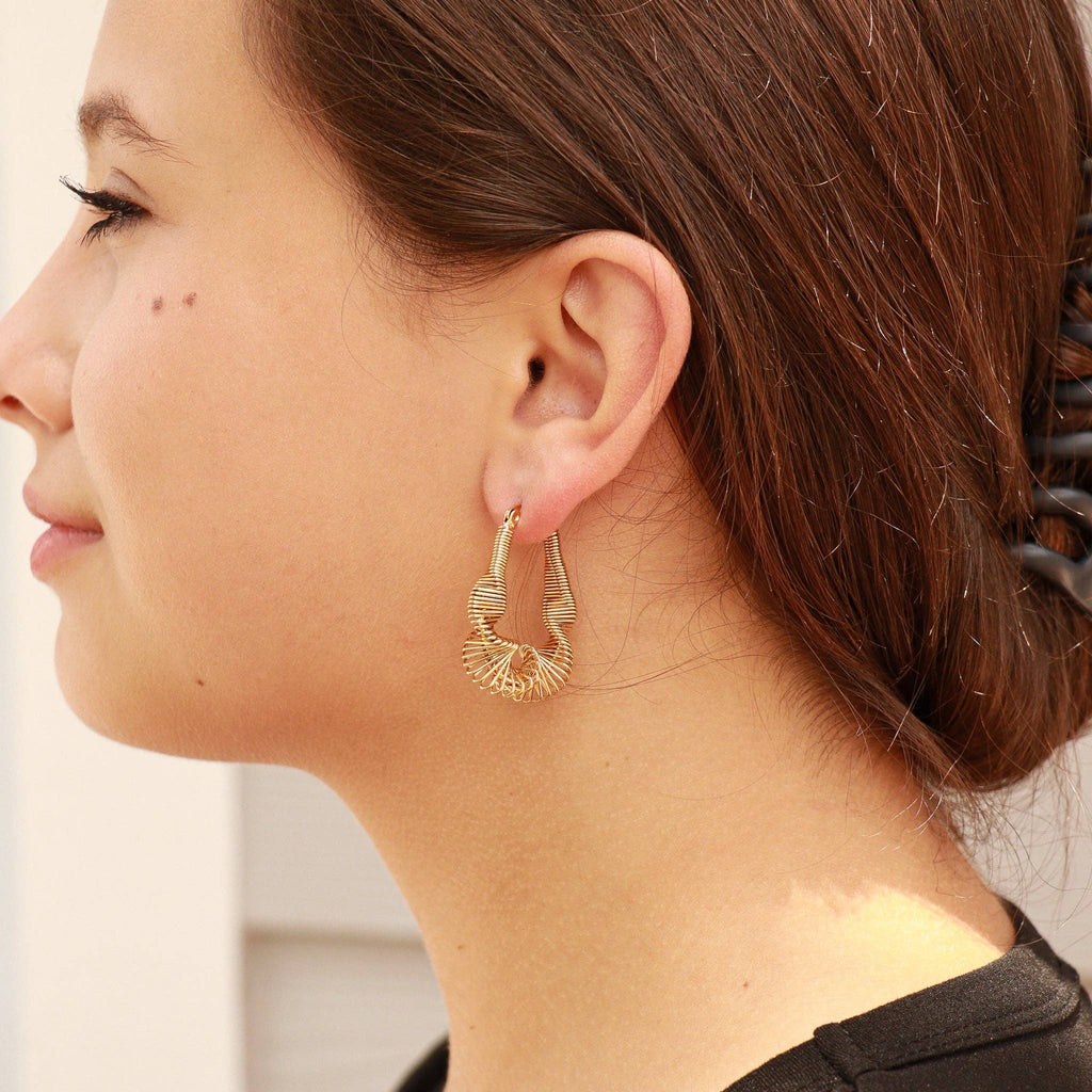 Woman wearing gold wired twisted hoop earrings