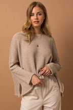 Woman wearing a taupe woven top  and pants against a brown background