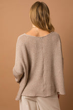 Woman wearing a taupe woven top showing back center seam detail against a brown background