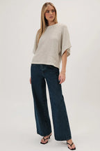 Woman wearing a natural boucle knit sweater and dark jeans on a white background