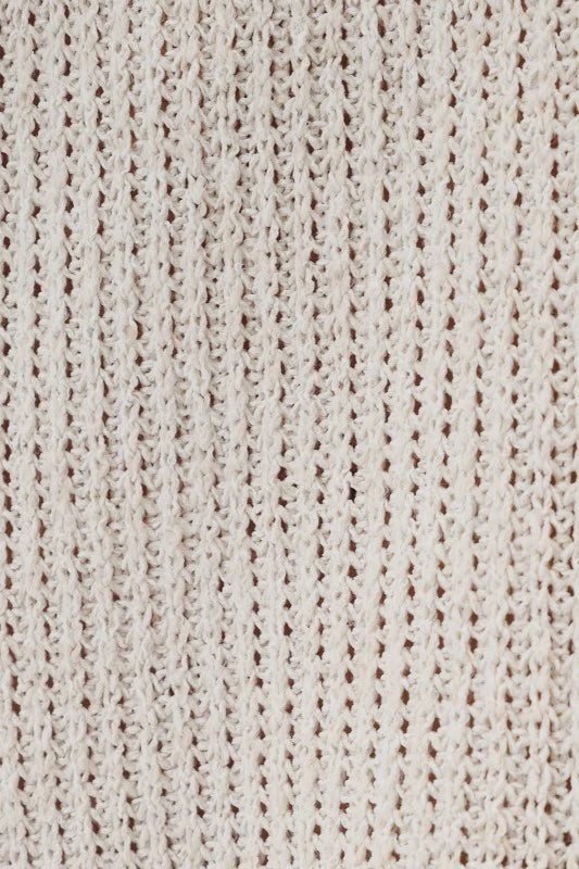Close-up of a natural-colored boucle knit fabric with a textured openwork pattern.