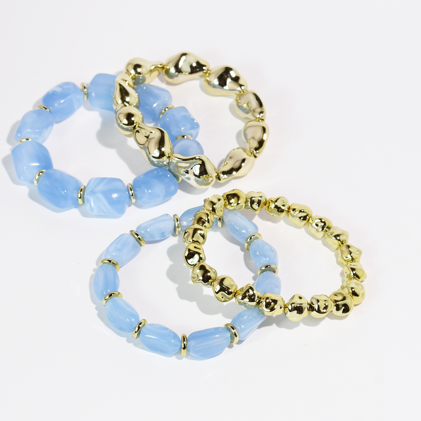 Set of two blue beaded gemstone bracelets and two gold tone bracelets on a white background