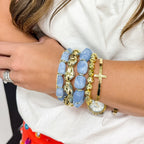 Close-up of a wrist wearing two blue bead gemstone bracelets and two gold tone bracelets