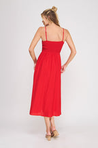 Back view of a woman wearing a red spaghetti strap midi dress on a white background