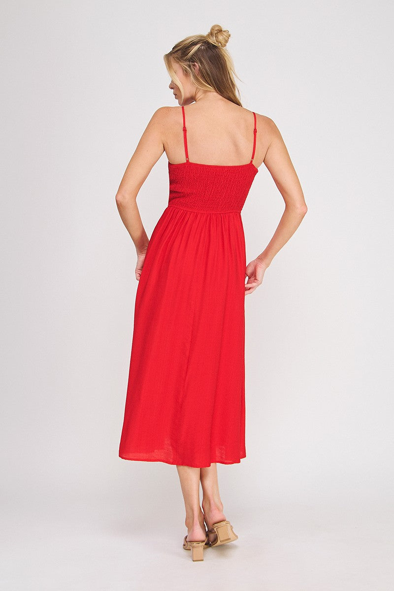 Back view of a woman wearing a red spaghetti strap midi dress on a white background