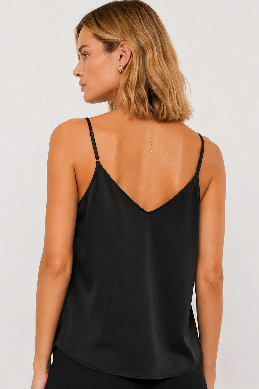 Back view of a woman wearing a black spaghetti strap tank top against a white background