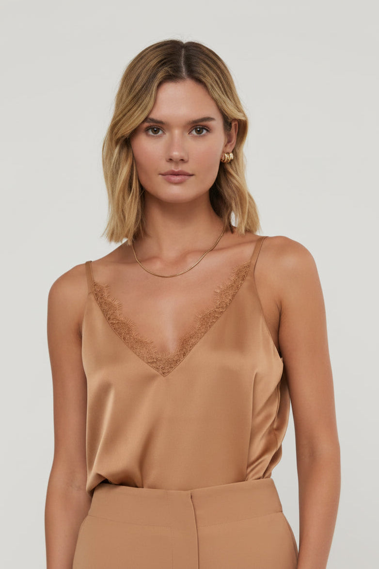 Woman wearing a lace trim camisole with spaghetti straps against a grey background