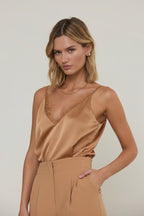 Woman wearing a lace trim camisole with spaghetti straps against a grey background