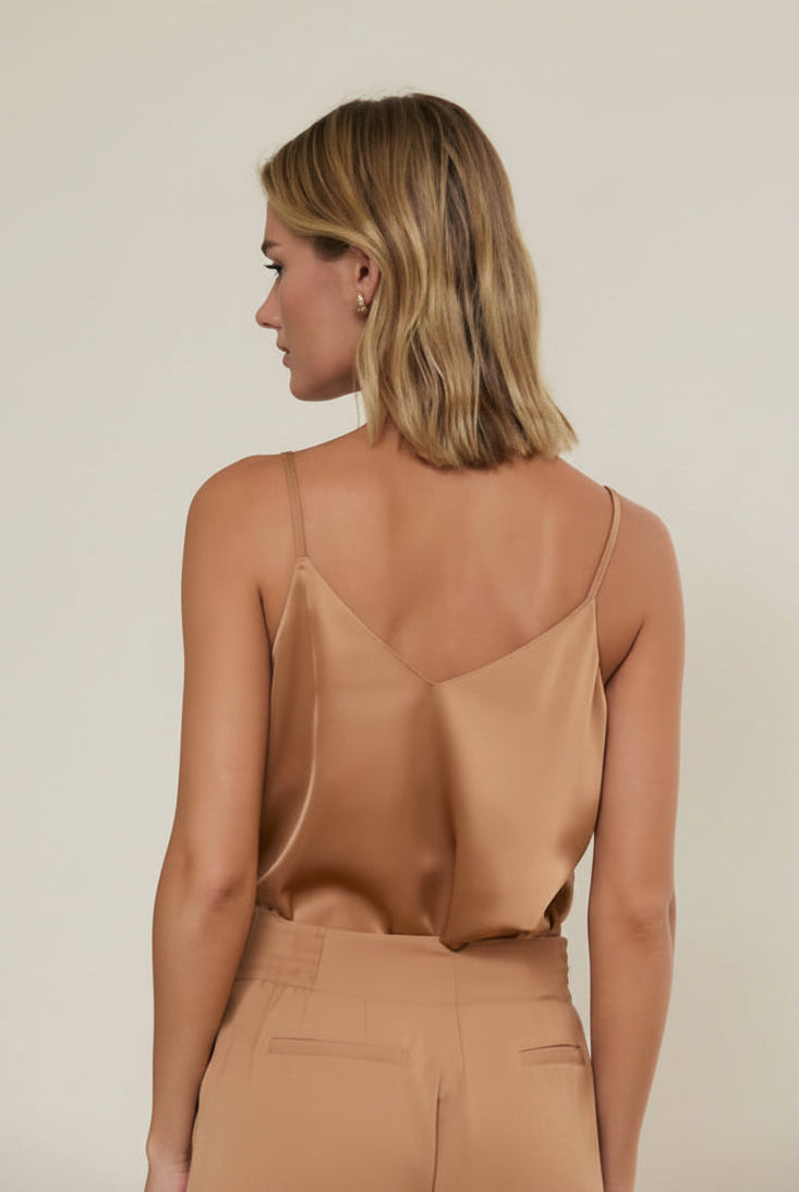 Back view of a woman wearing a lace trim camisole with spaghetti straps against a grey background