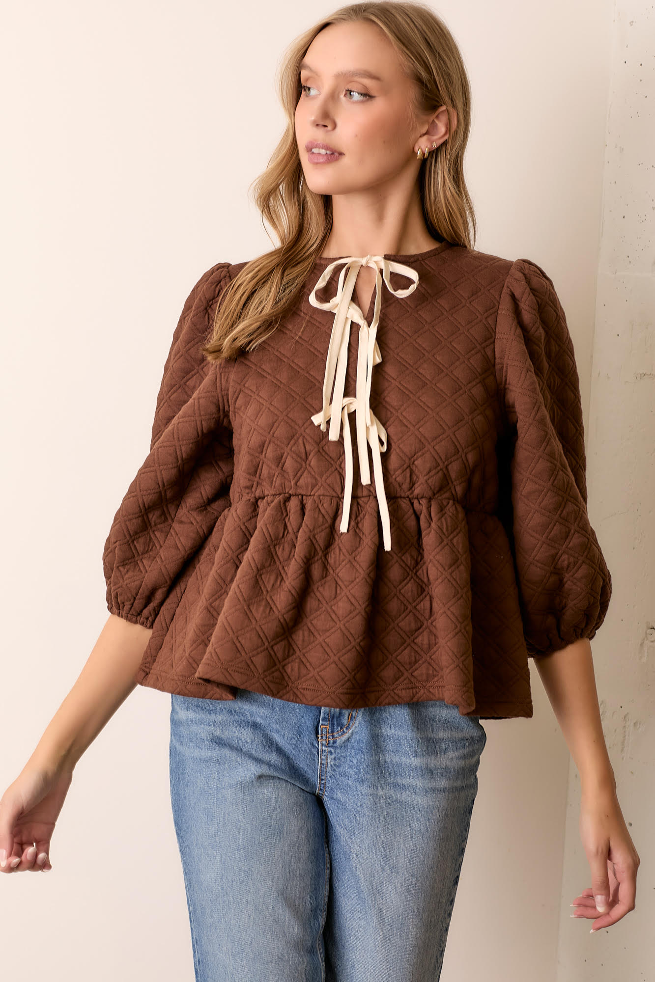Woman wearing brown quilted knit peplum tie top