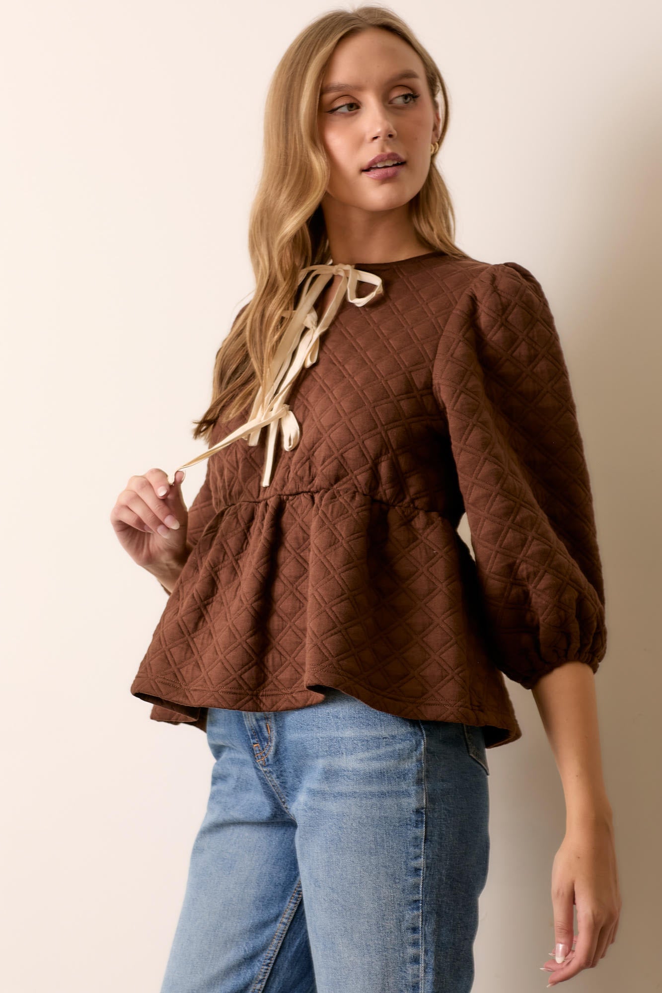 Woman wearing brown quilted knit peplum tie top
