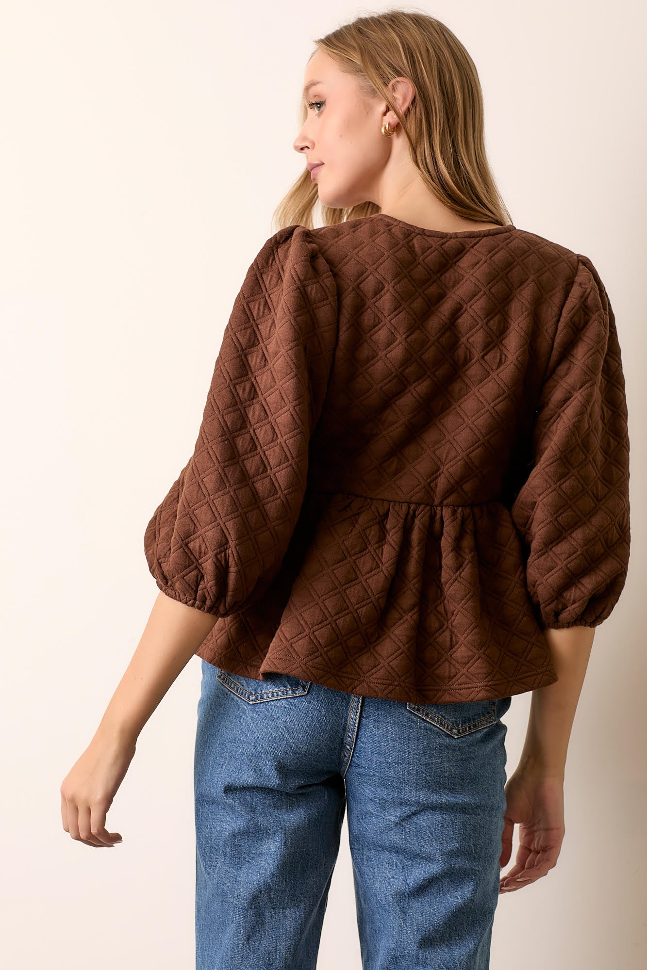 Woman wearing brown quilted knit peplum tie top