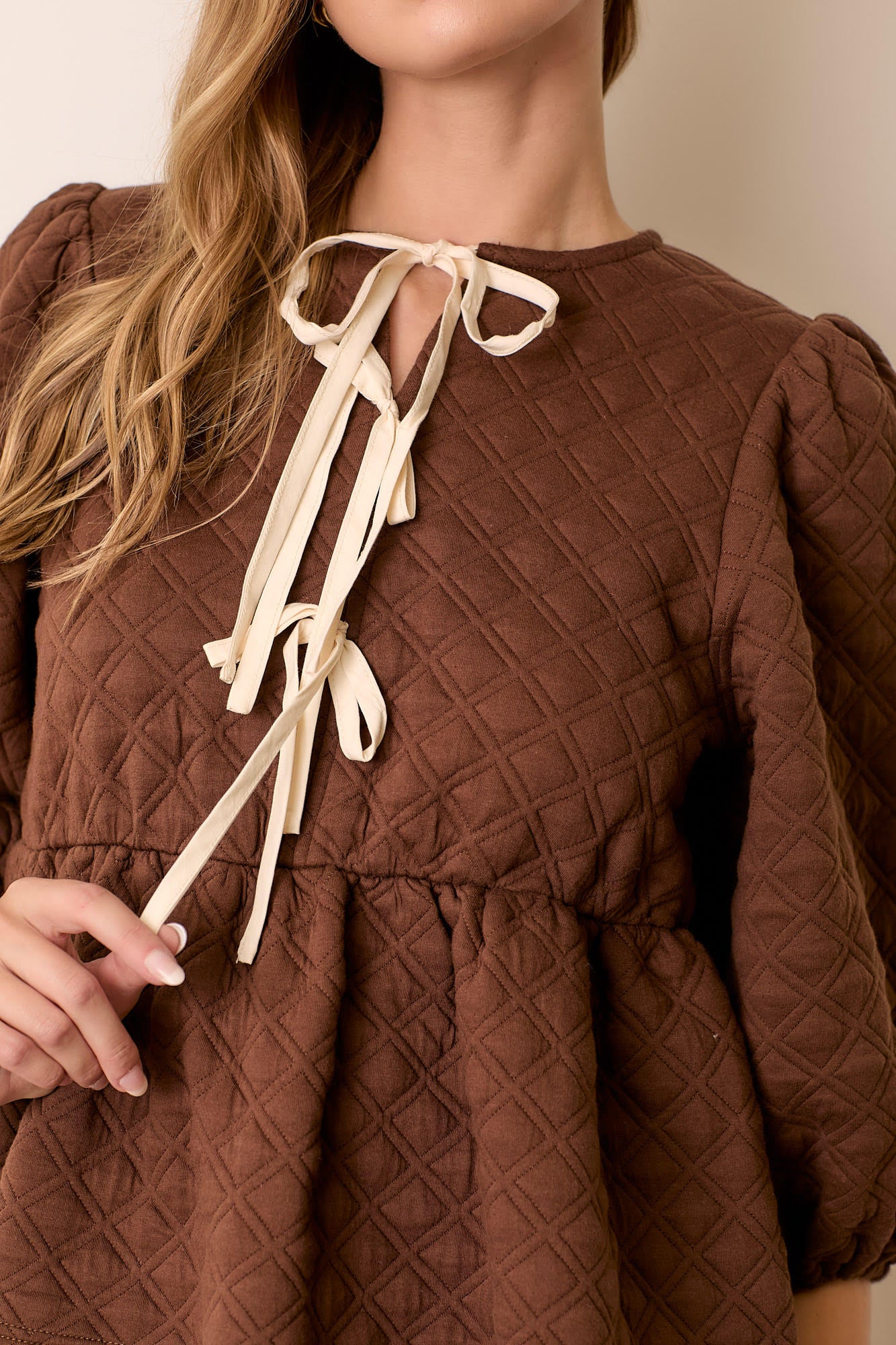 Woman wearing brown quilted knit peplum tie top
