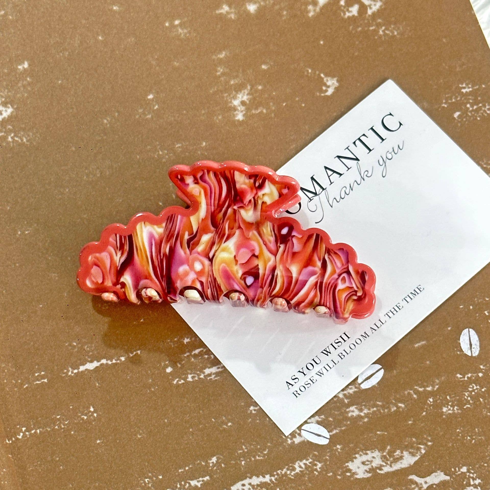 Colorful hair clip on a textured brown surface with a card underneath