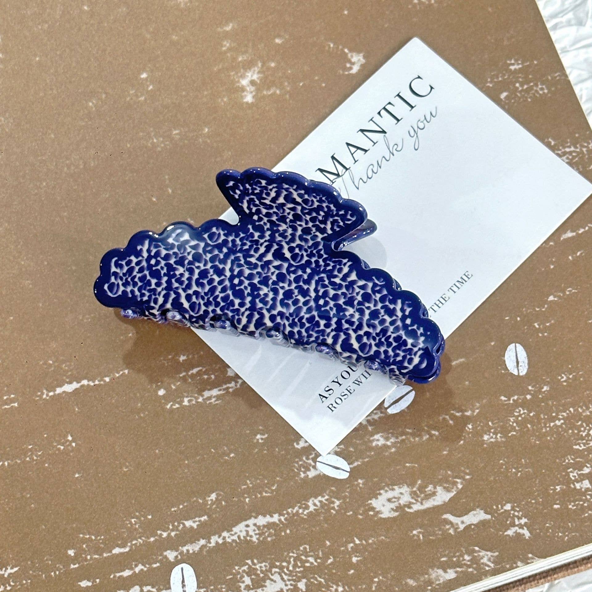 Blue colored hair clip on a brown surface with a card underneath