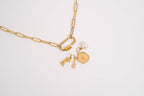 Paperclip carabiner gold chain necklace with charms on a light gray background