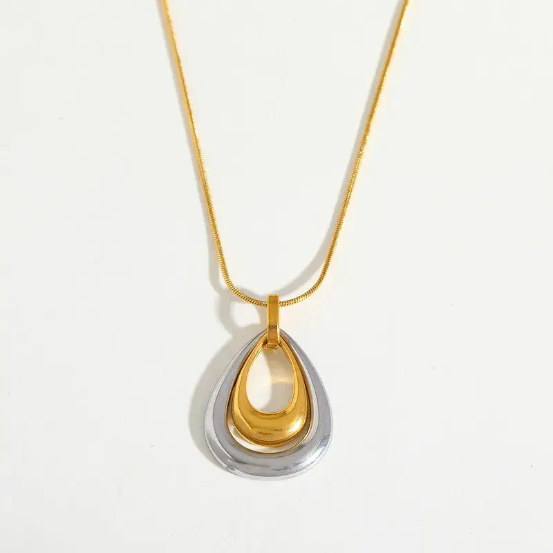 Woman's gold and silver teardrop pendant necklace on a white background
