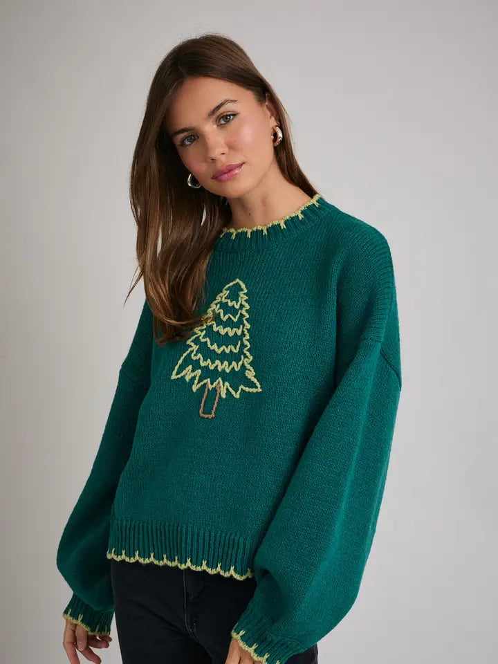 Woman wearing a green sweater with Christmas tree design on a gray background